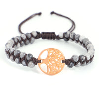 Hand-woven twine Tree of Life bracelet on a wooden tray with dried lavender and unglazed ceramic bowl, soft natural light