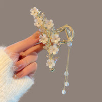 Handcrafted metal and pearl orchid bell tassel hair clip, resting on linen with incense smoke and natural stone, evoking quiet Eastern elegance